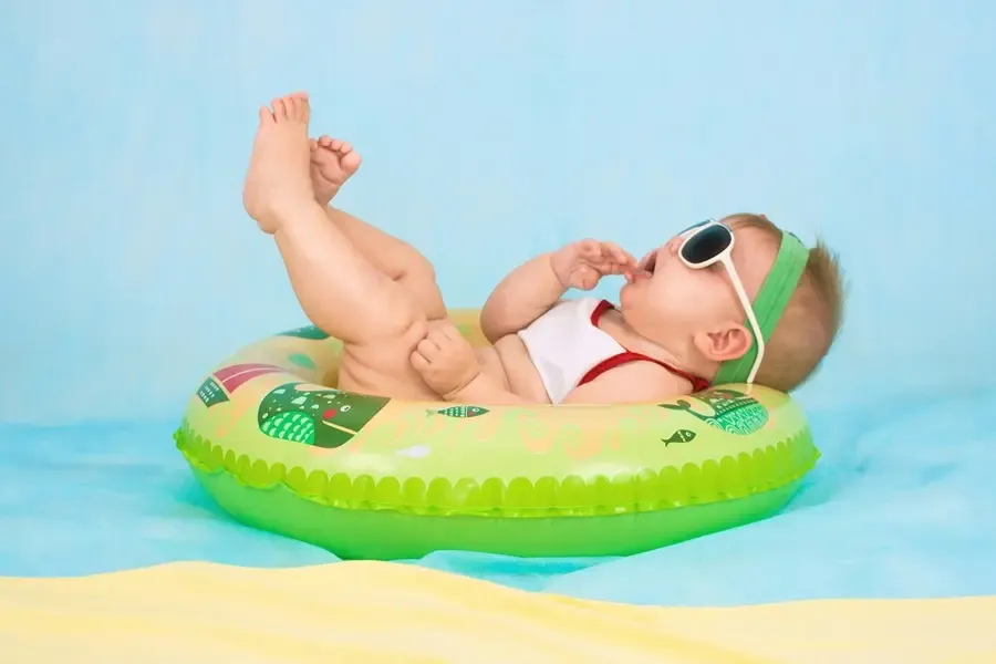 bébé portant des lunettes de soleil qui flotte sur une bouée dans une piscine