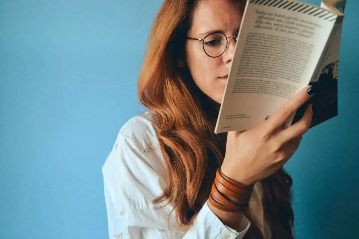 femme lisant un livre très proche de ses yeux